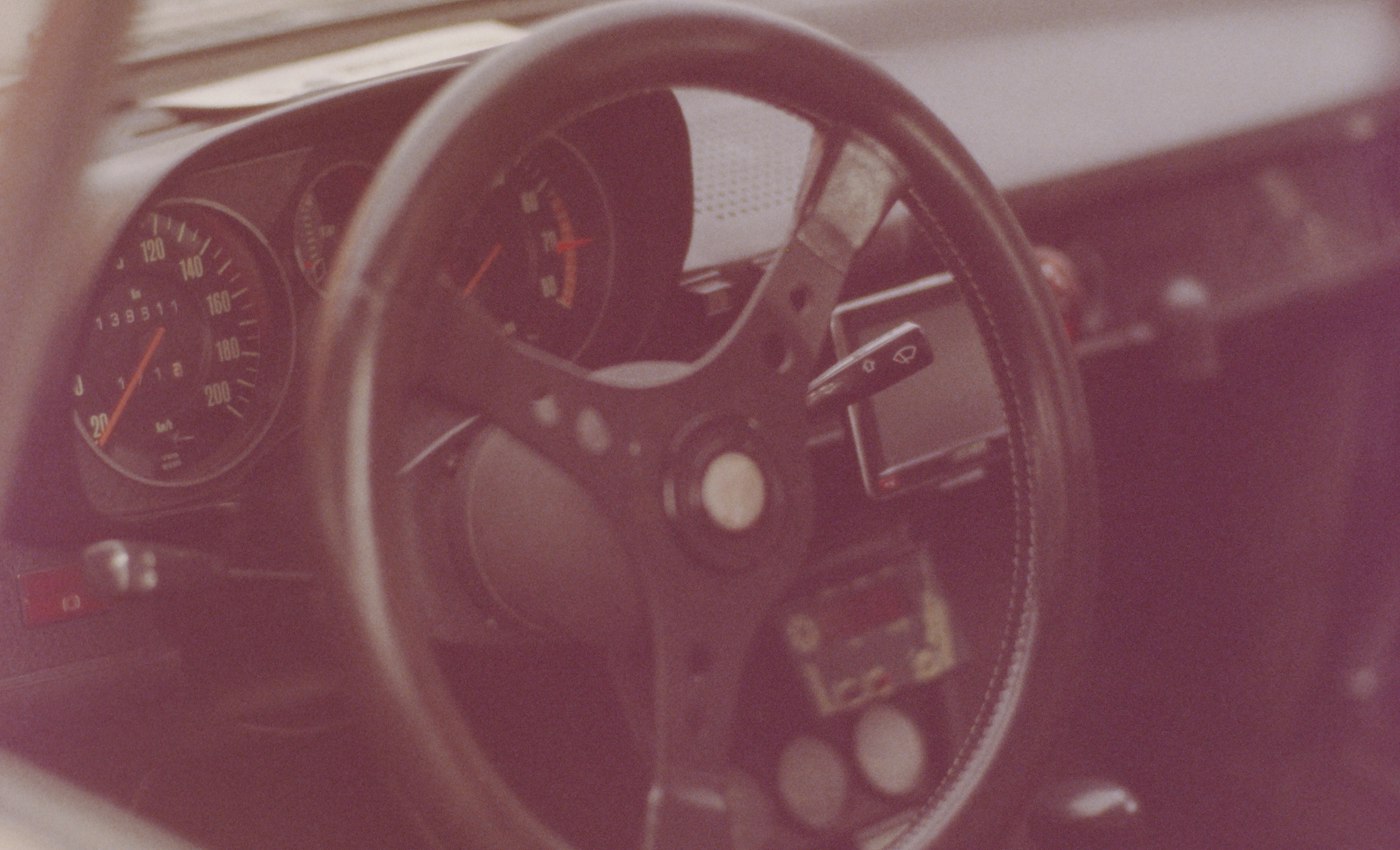 A close-up of a classic car steering wheel and instrument panel